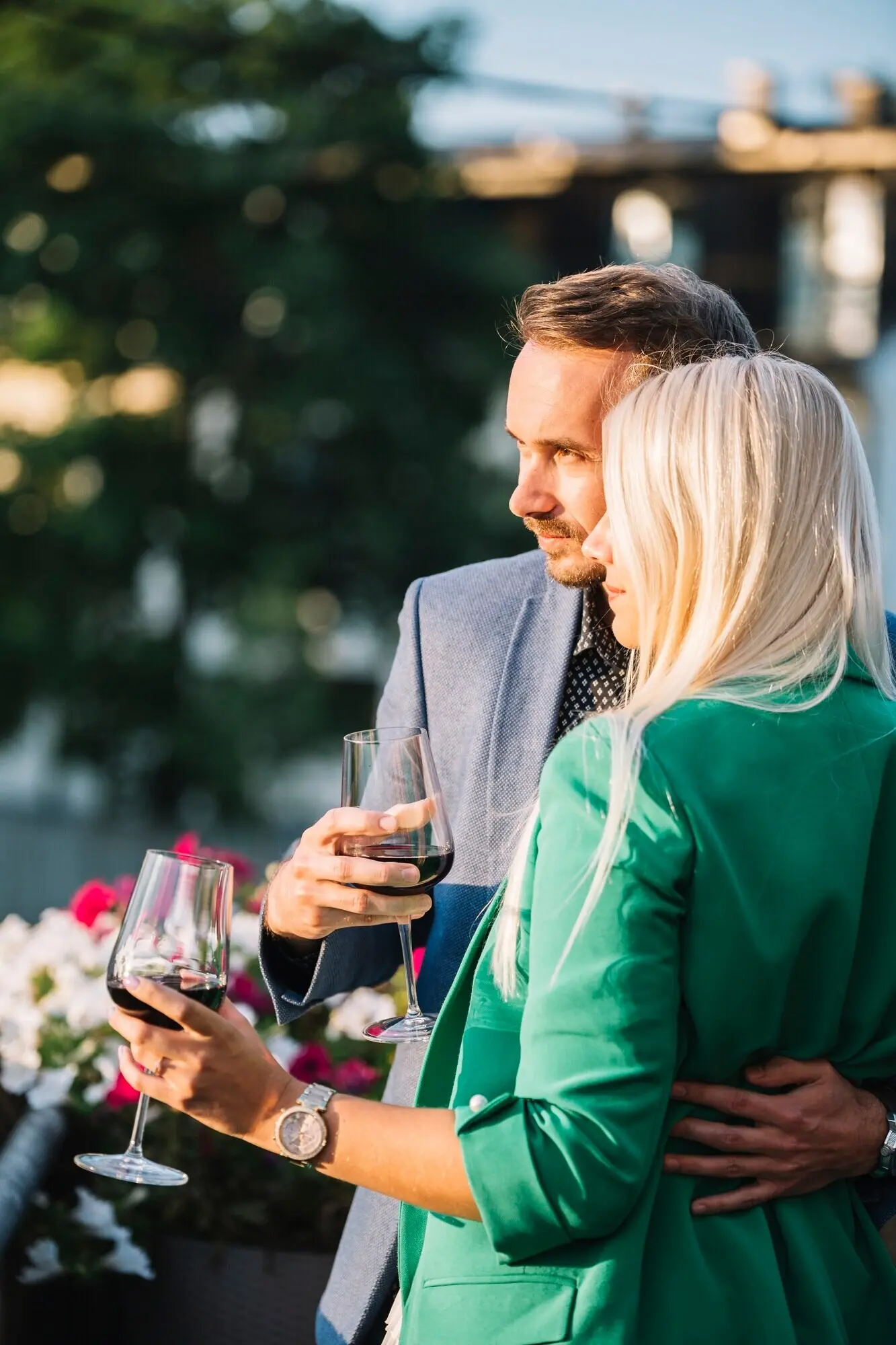 A portrait of a couple embracing while holding wine glasses.
